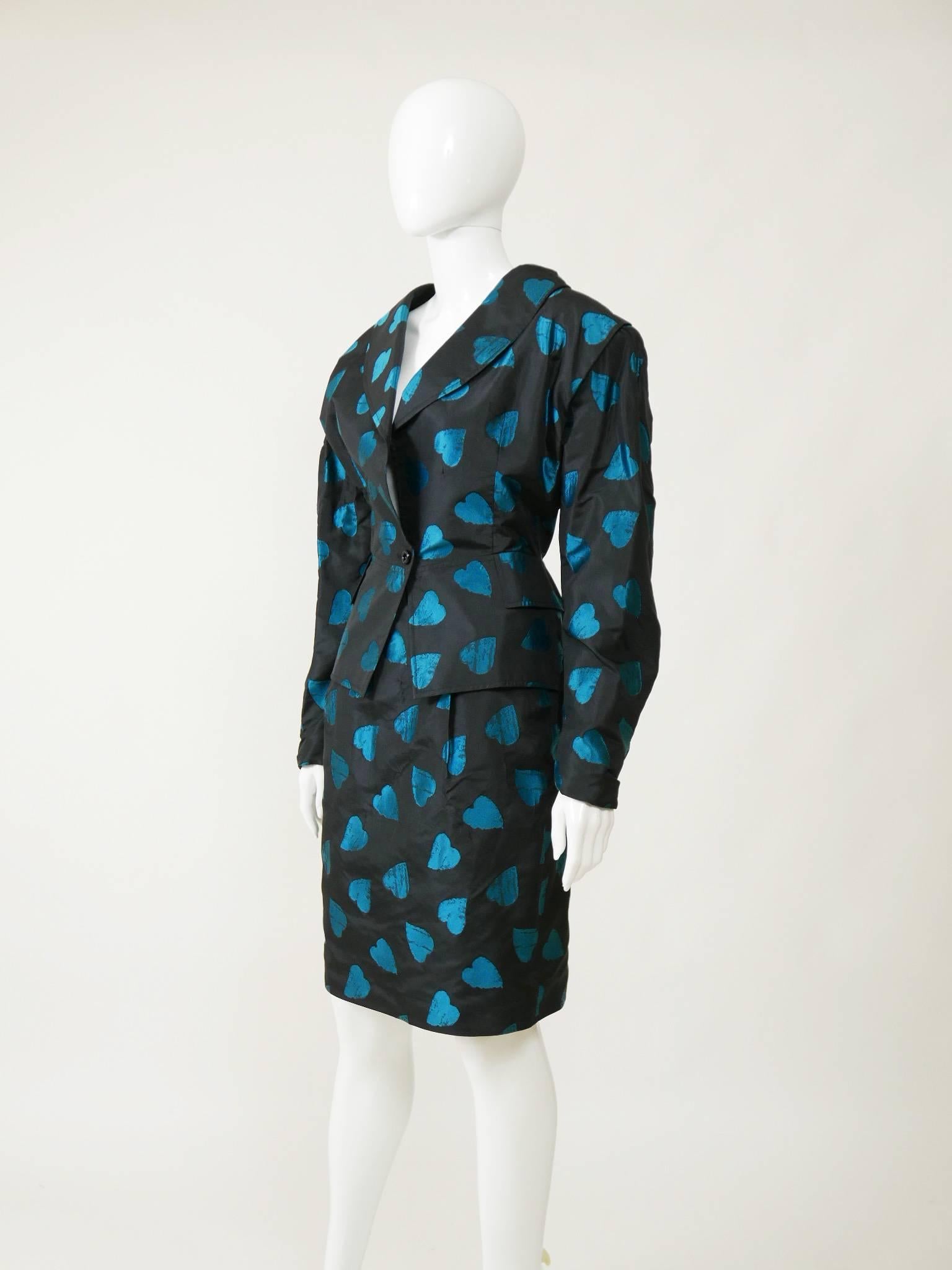 This amazing, sexy and feminine set of Umanuel Ungaro from the late 1980s has a typical oversize 80s style. It's in black silk taffeta with turquoise hearts print. The peplum jacket has padded shoulders and one button closure, faux frontal pockets