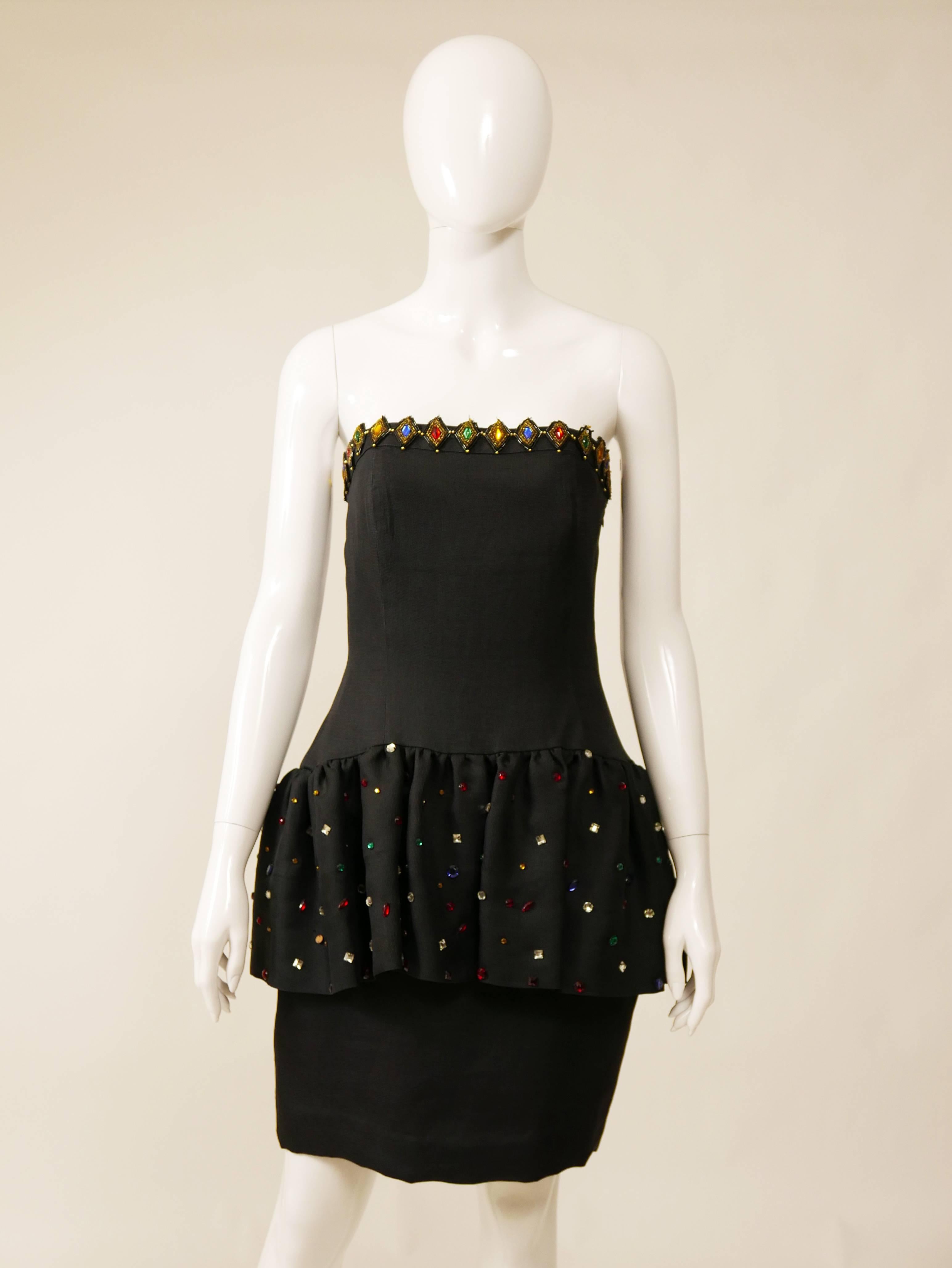 This amazing Saint Laurent 1980s cocktail dress is in a black silk fabric with beadeds and rhinestones details. The strapless top is straight across and has ruffled skirt over pencil skirt and is satin lined. 

Very Good vintage