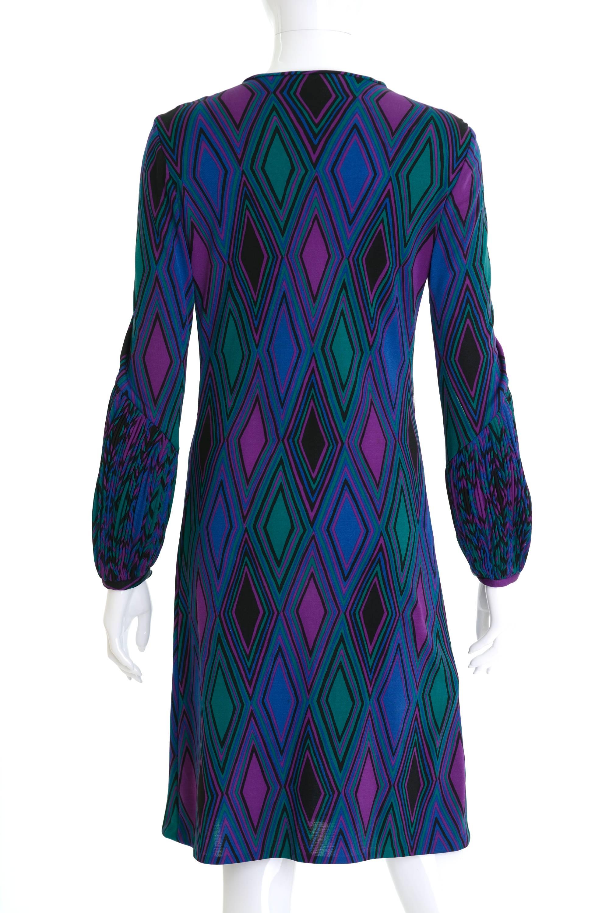 This lovely 1970s Ken Scott dress is made of green and purple geometric print jersey fabric. It has long sleeves with pleated details and button neck closure.

KEN SCOTT it is a cult
«The maestro of ultra floral prints… aristocratizes evenwild