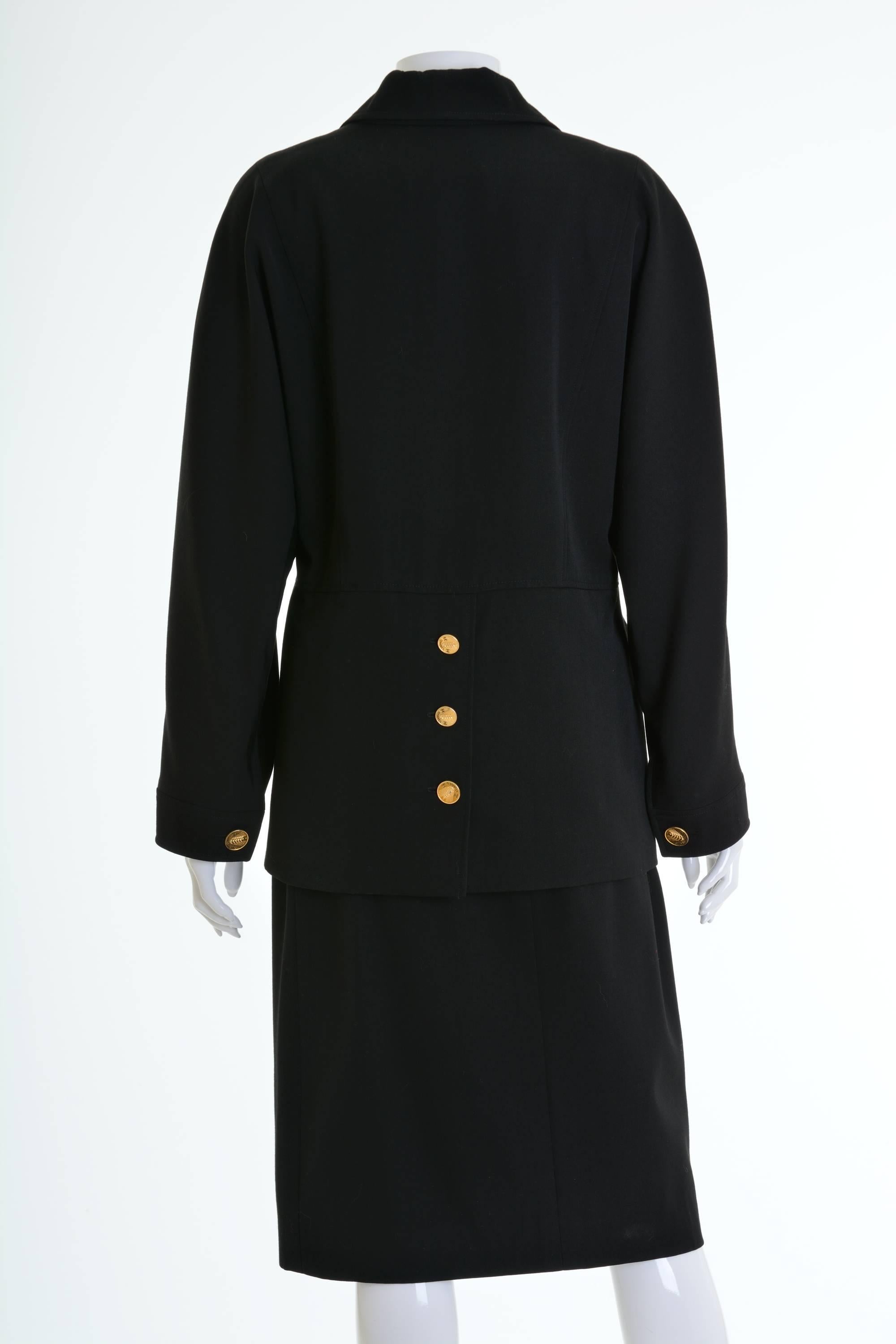 This lovely and authentic Chanel suit dress is in a black wool gabardine fabric. The jacket has oversize line,dolman sleeves,  two front flap pockets, double breasted closure with CC logo golden metal buttons and on the back slit. The pencil skirt