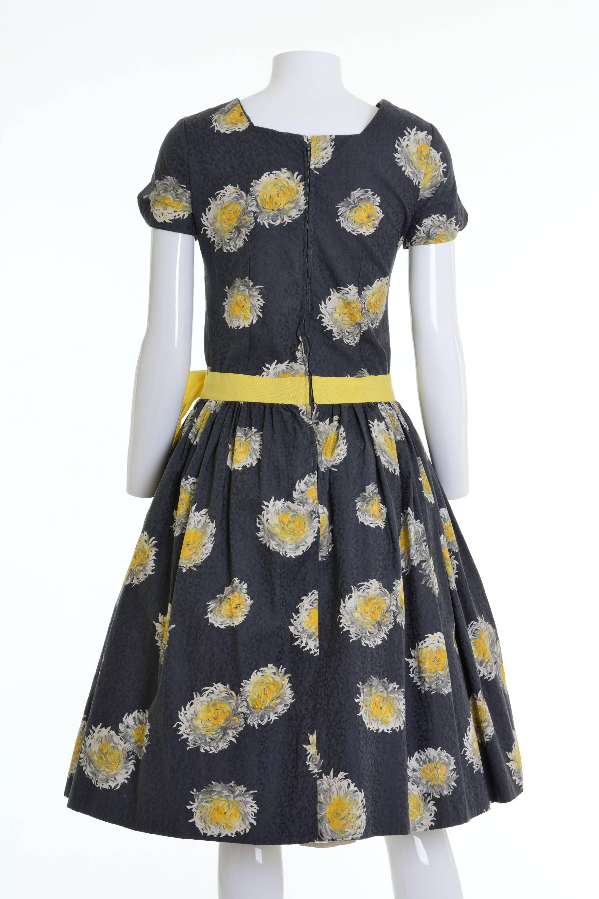 1950s cocktail dress in a grey cotton pique fabric with painted flower textile, yellow waist strap, back zip closure, fully skirt with a lot of fabric in the hem, to be able to stretch.

Excellent Vintage Condition 

Label: Unknown 
Fabric:
