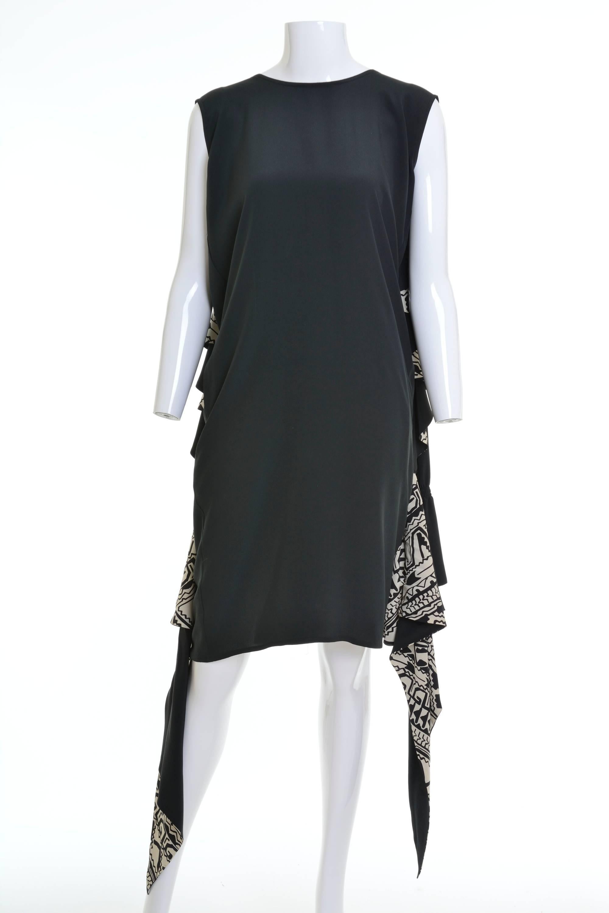 1980s Cadette dress in a black and white silk fabric, tunic dress with side pockets, it has overcoat is stitched on the shoulders of the dress to let it hang easily behind, turn up cuff with a black and white abstract pattern, ruffle opening and