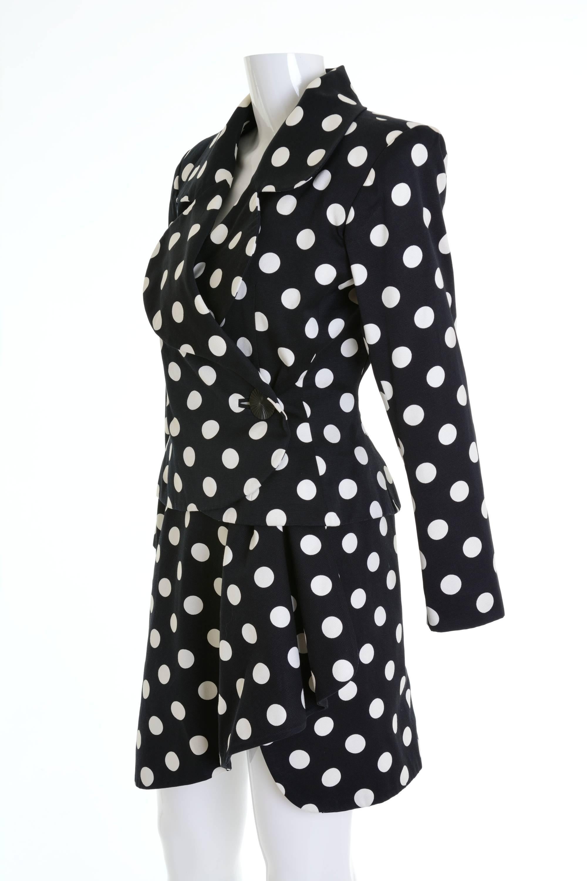 This lovely early 1990s Yves Saint Laurent Rive Gauche suit dress is in a black pique cotton fabric with white polka dots print. It has fitted jacket with padded shoulders and wrap mini skirt. It's fully satin lined.

Excellent vintage