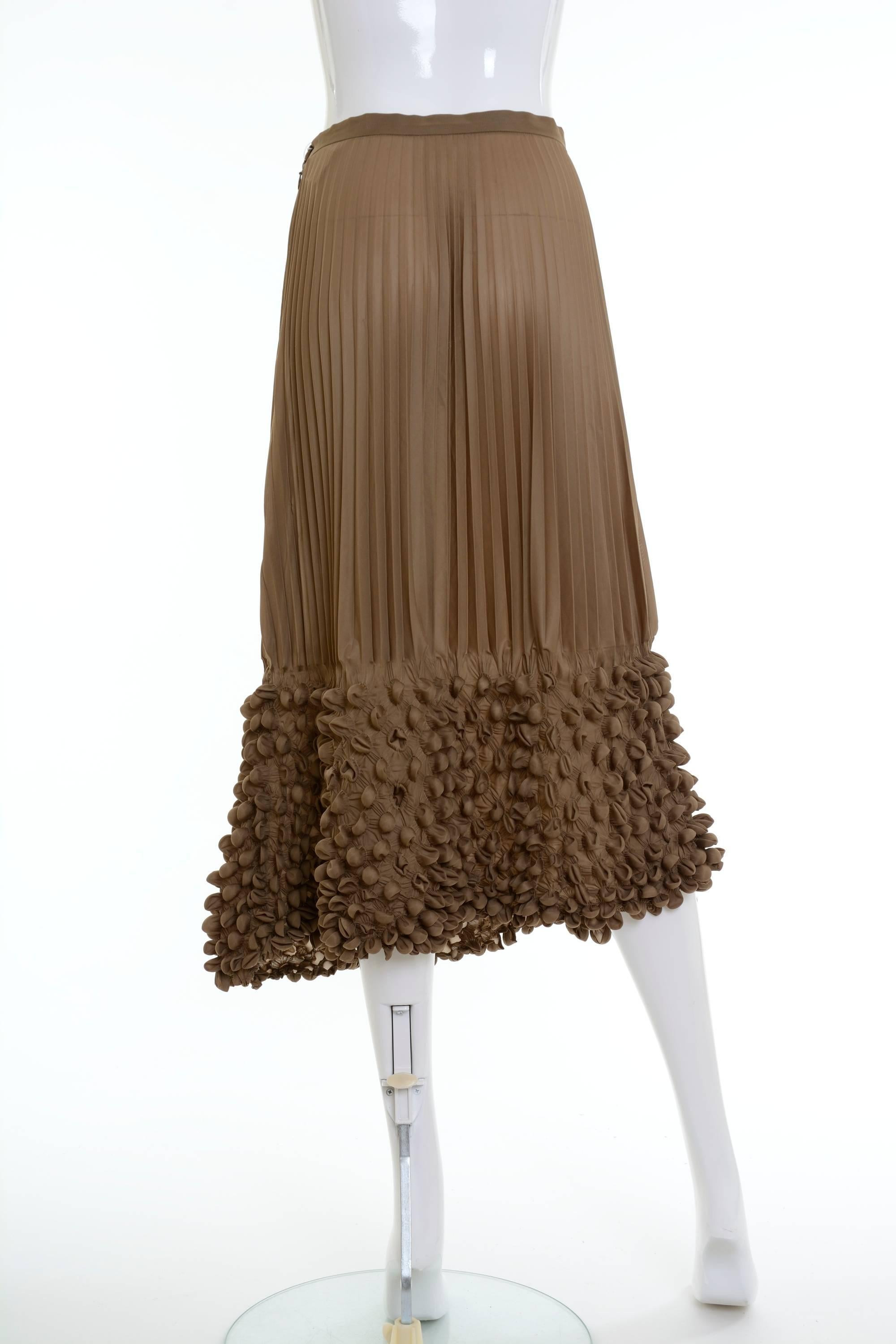 This amazing Issey Miyake skirt is a typical example of the reverse pleating technique he developed in the 1980s. It's in a brown pleated fabric with origami technique details. It has zip and button side closure. 

Excellent vintage