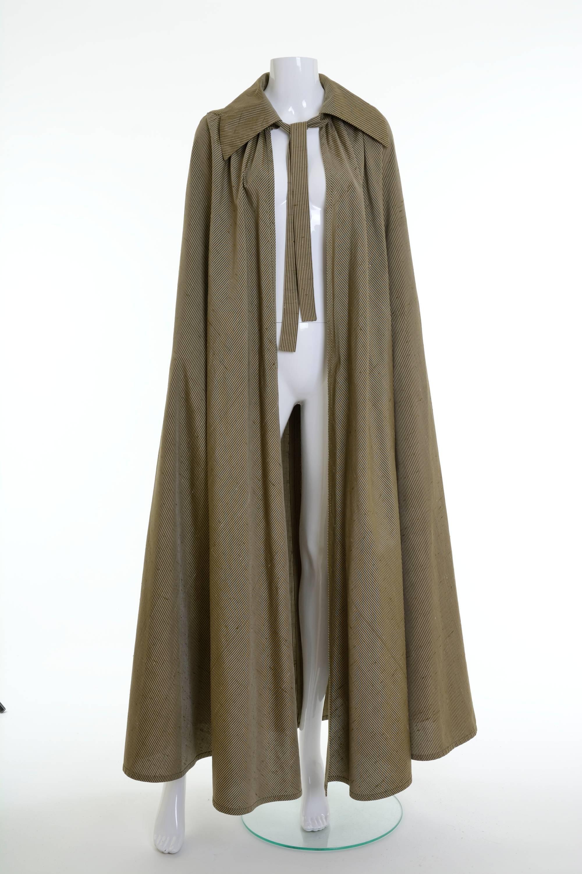 This fabulous Mila Shön 2 pc set is in olive green striped print silk fabric. The long pleateds skirt has two large frontal pockets, back zip and hooks closure and is satin lined. The long cape has tie collar.

Excellent vintage condition

Label: