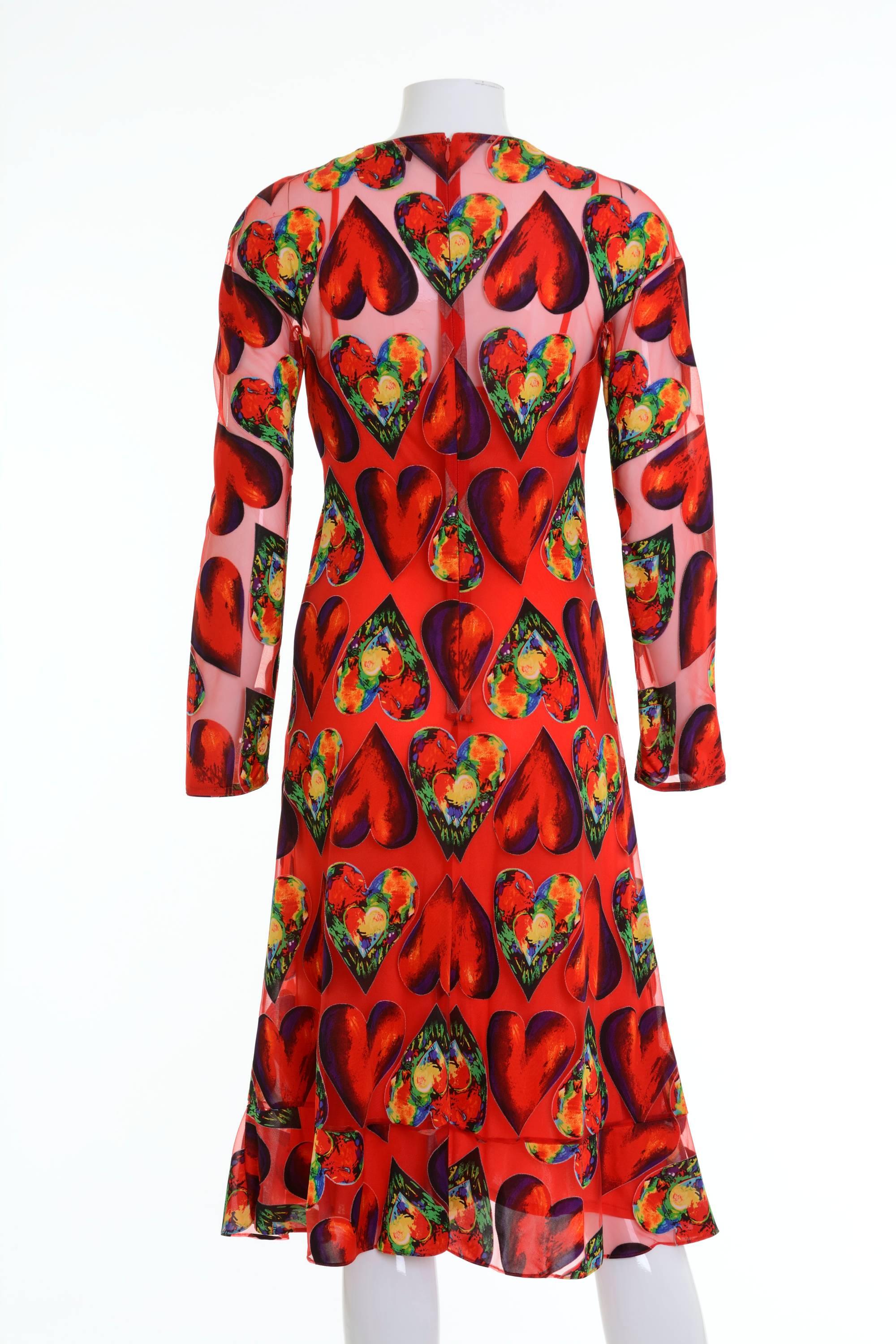 This amazing brightly colored dress from 1994 Gianni Versace collection in a synthetic blend. There are alternating hearts in red and bold colors on a sheer red background. The dress is long sleeved with a scoop neckline and a 5