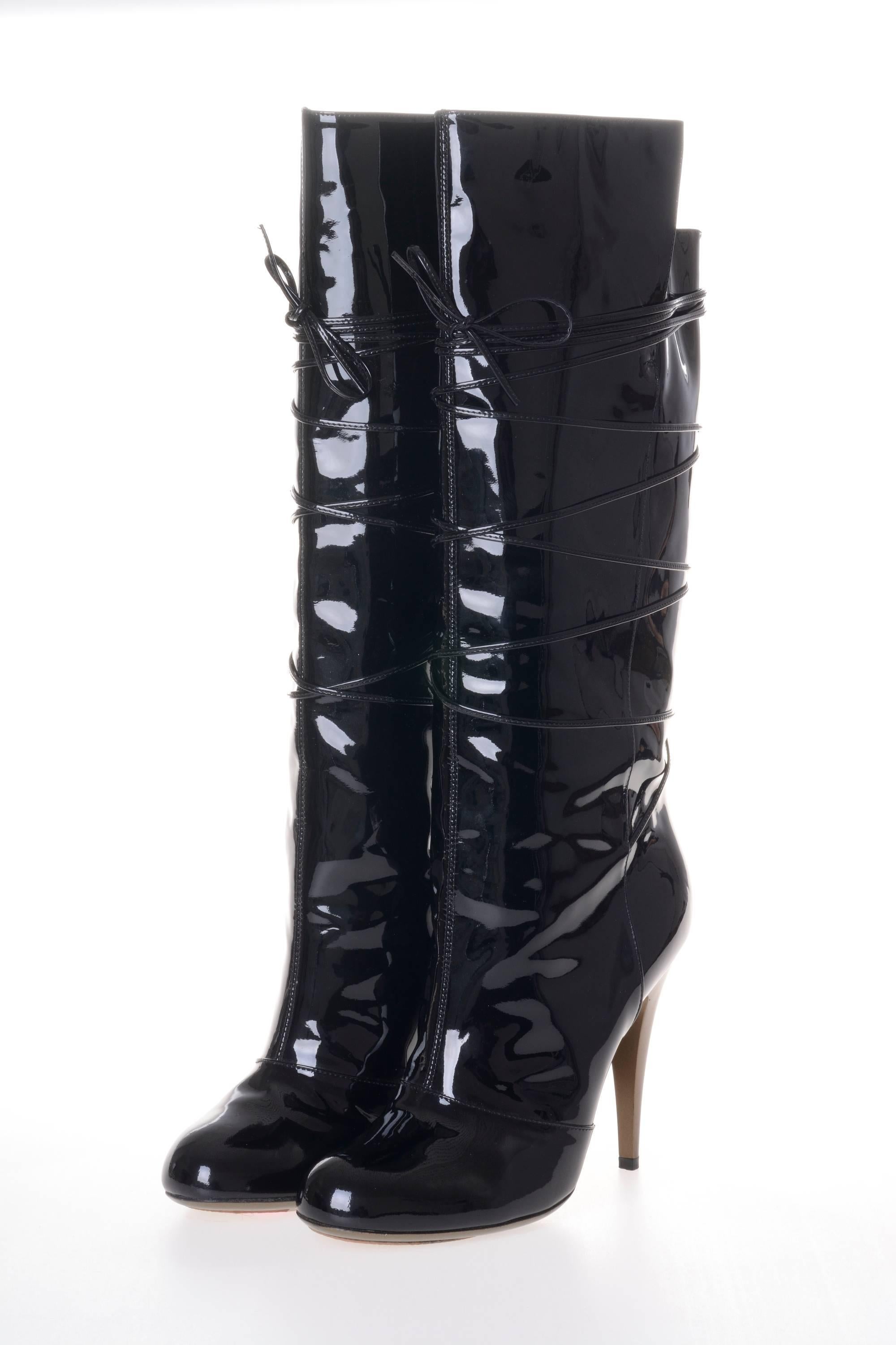 This black patent leather crisscross lace boots by YVES SAINT LAURENT Rive Gauche has a lace cross up the boots from the ankle, almond toe shape, stiletto high heel, fully lined with gold leather, old gold outsole and decorative sewing on each
