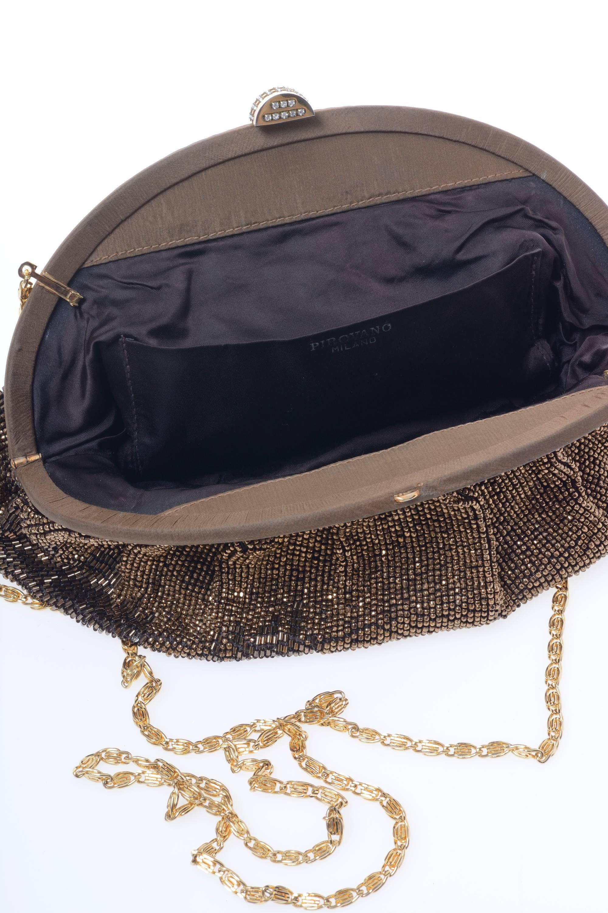 This 1960s amazing clutch bag has a gold chain shoulder strap that could be hidden inside, the bag is made of taffeta textile totally embroidered with old gold seed beads, a pocket inside and minaudière closure with silver gems details on. It's