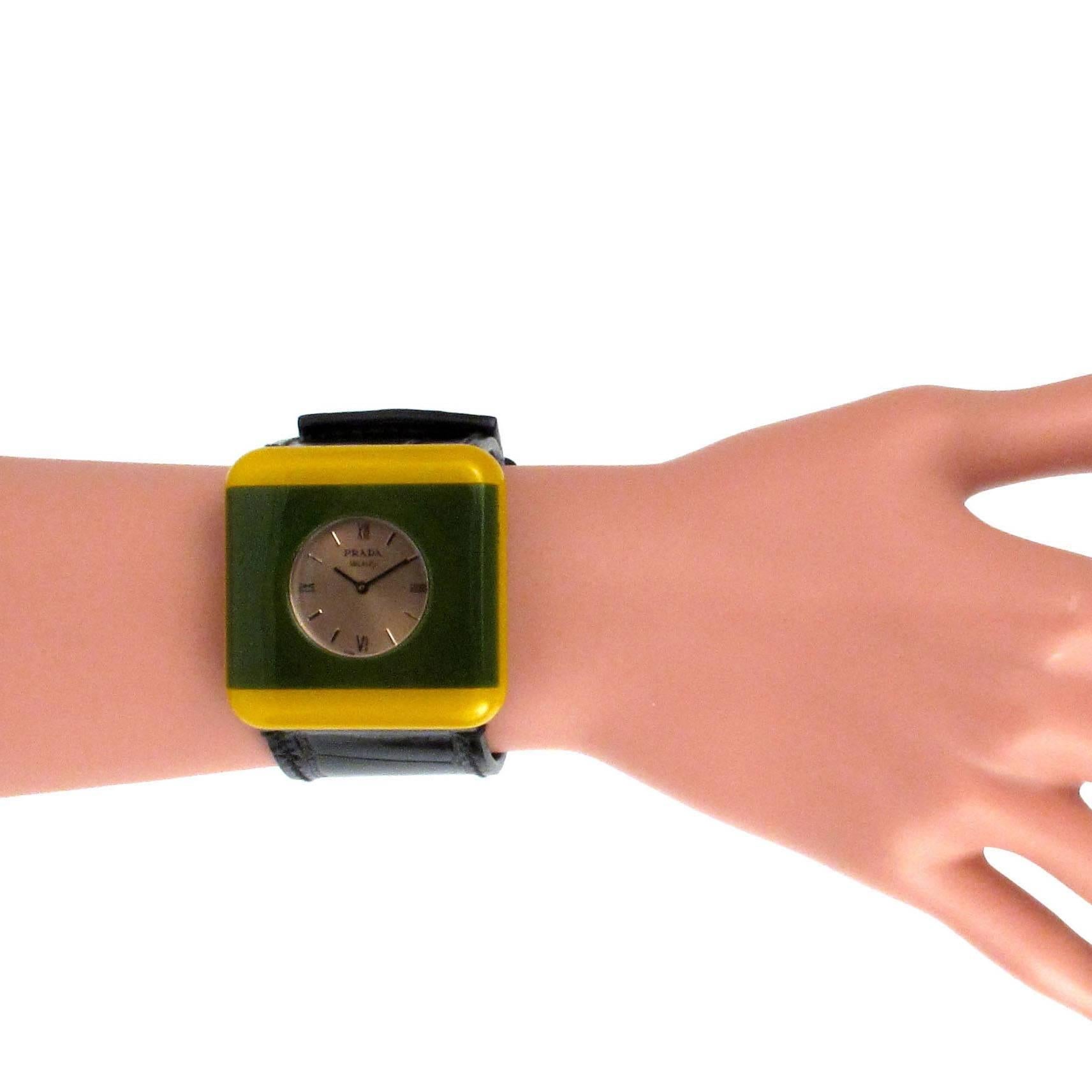 Prada - Watch Bracelet

Color: Green / Yellow / Black

Material: Resin / Leather

------------------------------------------------------------

Details:

- leather band

- two tone watch face

- roman numerals

- stainless steel