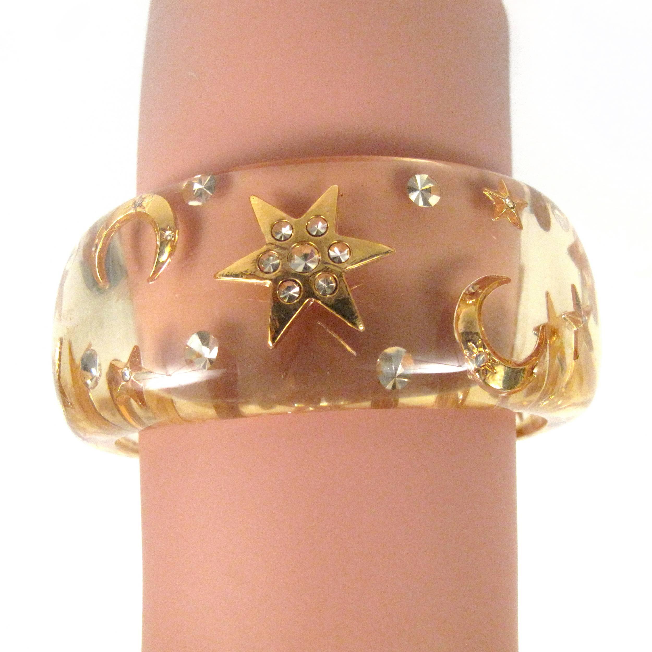 Chanel - Vintage Cuff Bracelet

Color: Clear / Gold

------------------------------------------------------------
 
Details:

- gold tone metal

- cc logos throughout

- star & moon symbols throughout

- crystals embellishments