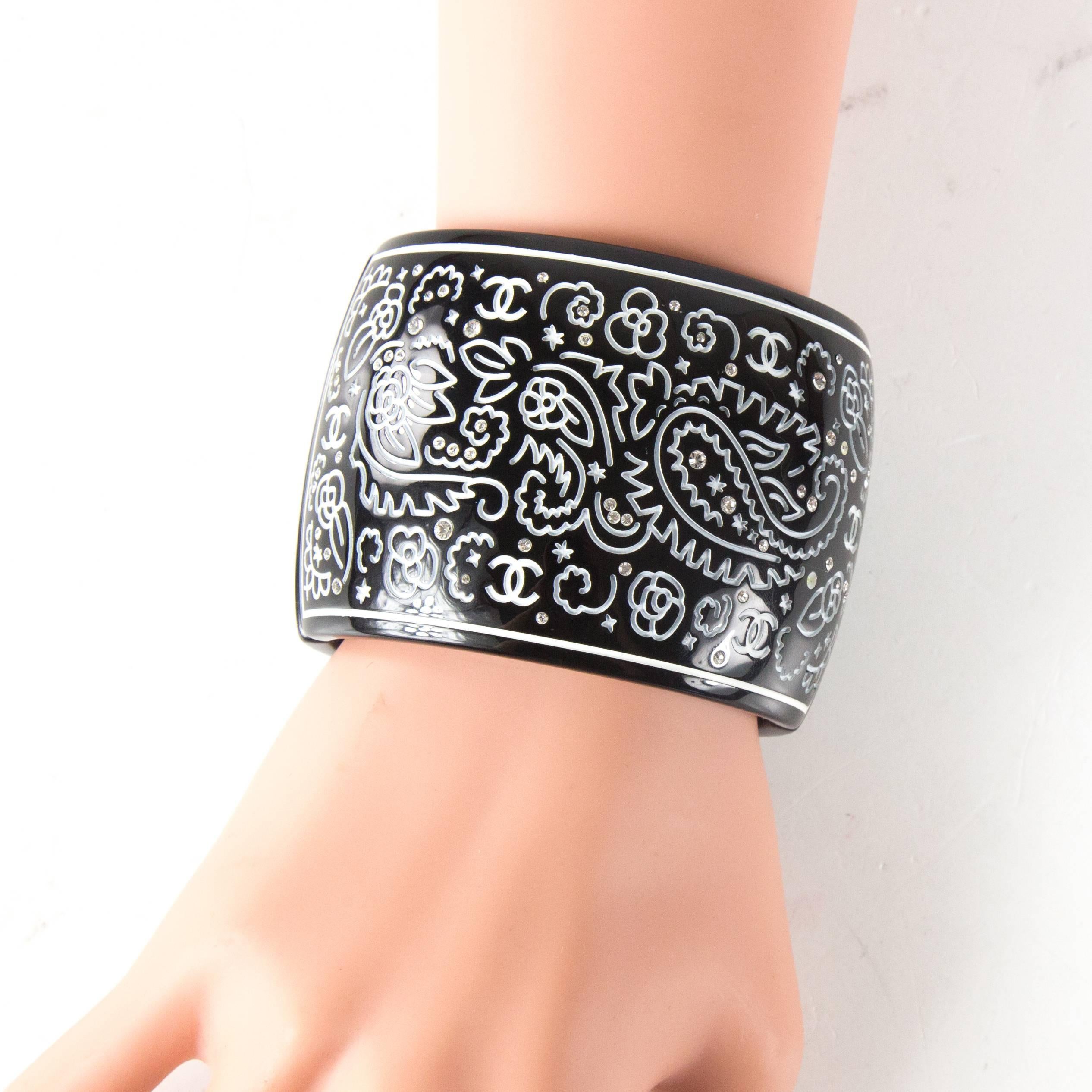 Chanel - Crystal Carved Wide Cuff Bracelet

Color: Black / White

Material: Resin / Crystal

------------------------------------------------------------
 
Details:

- carved paisley design throughout

- CC logos carved throughout

-