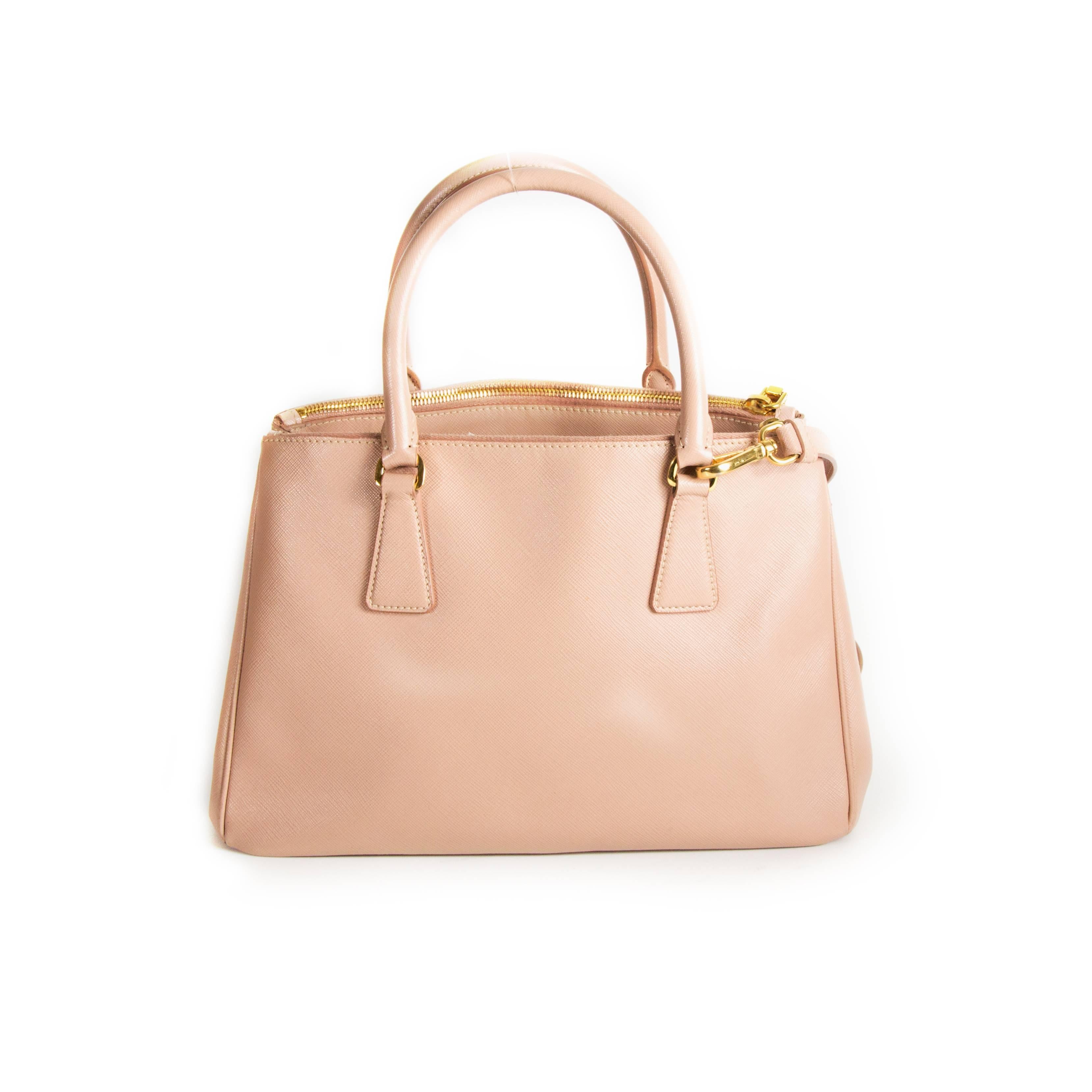 Prada - Satchel Bag

Color: Pale Pink

Material: Saffiano Leather

------------------------------------------------------------

Details:

- gold tone hardware

- dual rolled handles

- removable shoulder strap

- zip top