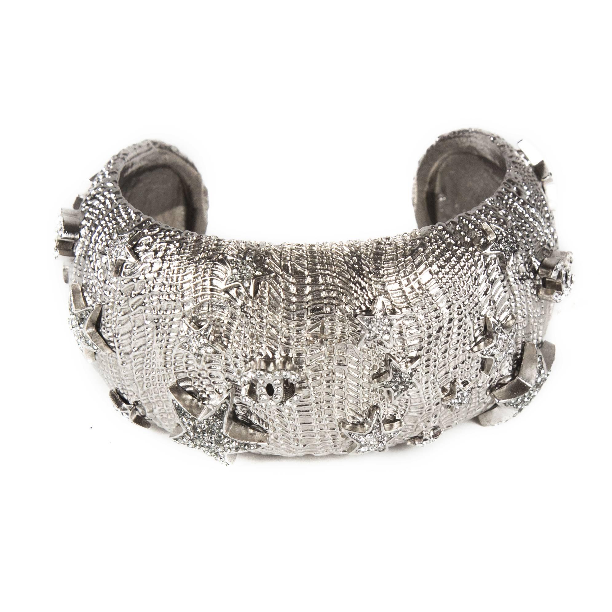 Chanel - Star Cuff Wide Bracelet

Color: Silver

Material: Metal

------------------------------------------------------------
 
Details:

- silver tone hardware

- crystal embellishments throughout

- cc logos & stars throughout

-