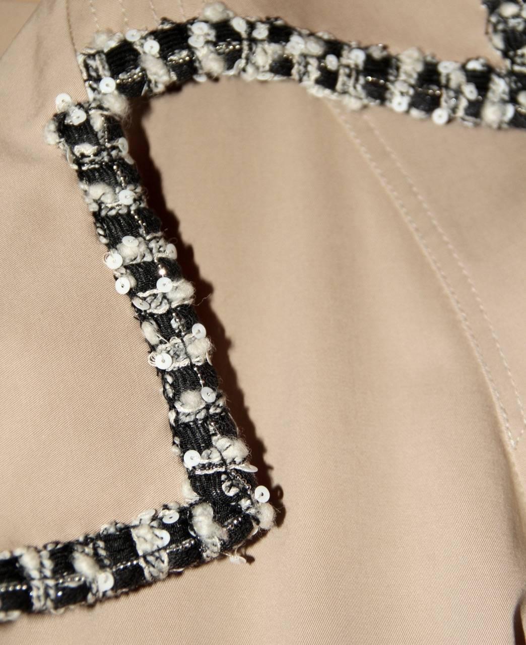 Elegant and timeless double-brested trench coat from Chanel Spring 2004 Collection. 
Featuring a black and white tweed trim with sequin embellishments, shoulder epaulettes, two pockets and a waist belt. 

Collection: Spring 2004 
Fabric: 95% cotton,