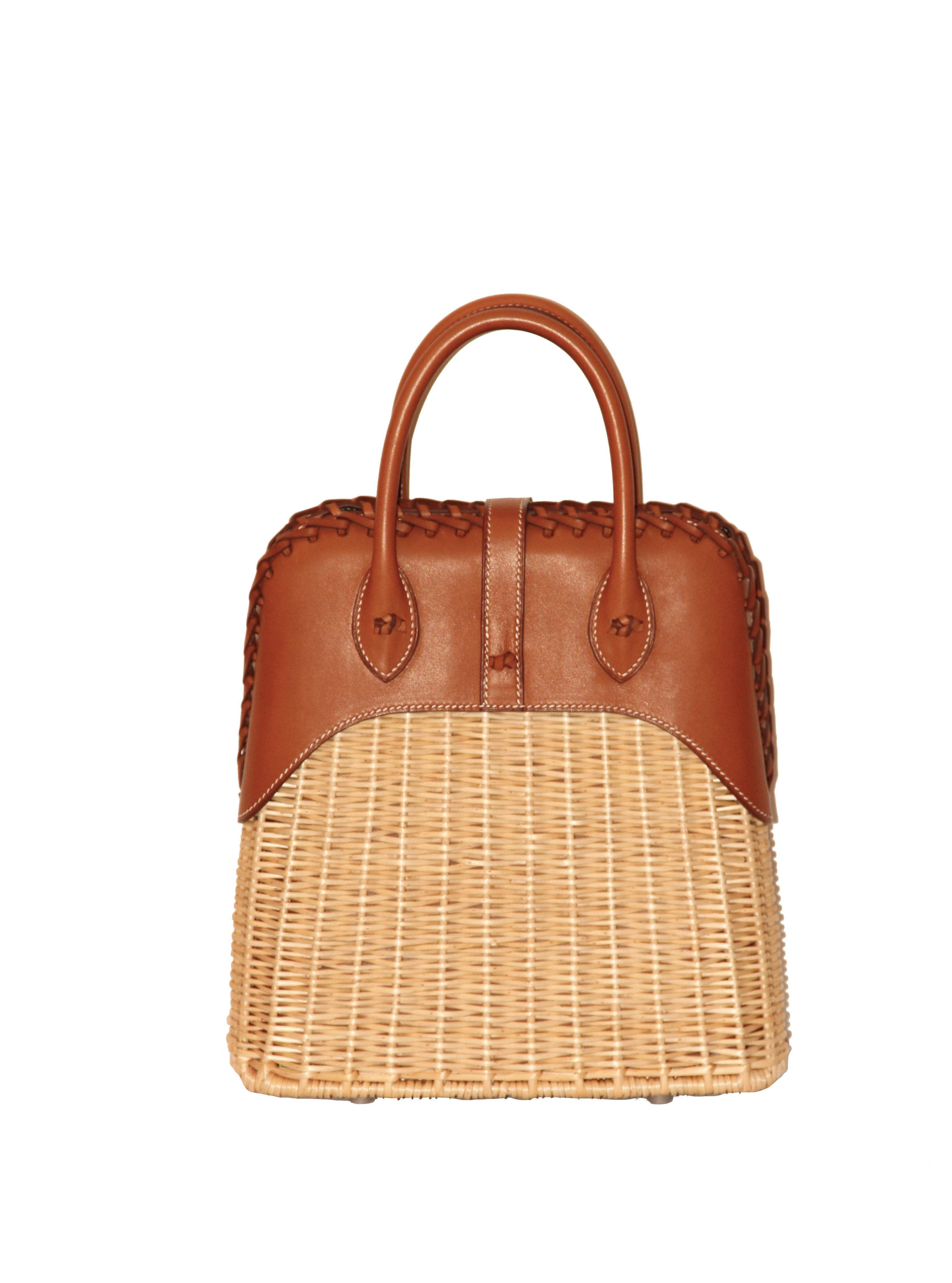 This exquisite and amazing Bolide Picnic bag is made of Barenia leather and woven wicker.
The front leather strap closes with with a Clou de Selle button and a braided leather piece finishes the top of the bag.
The double handles are decorated with
