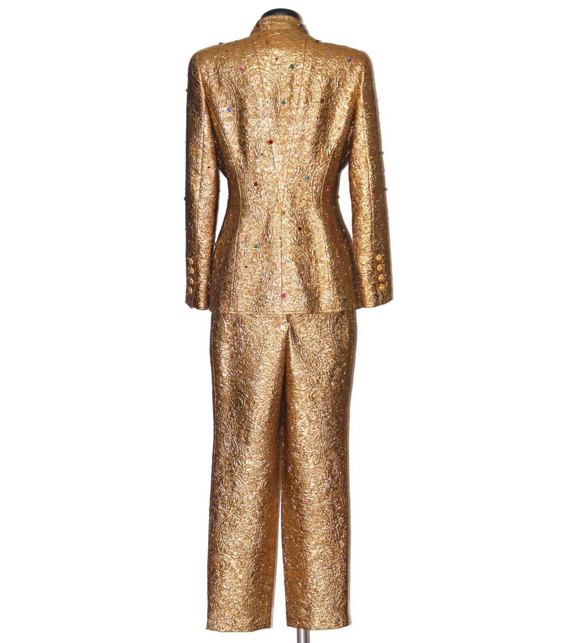 Exceptional collector's pantsuit from the Chanel Fall 1996 collection featuring an amazing tailored fit and jewels Gripoix buttons.
The jacket features some embroidered colored crystals, a mandarin collar, eleven gold Gripoix front buttons, four