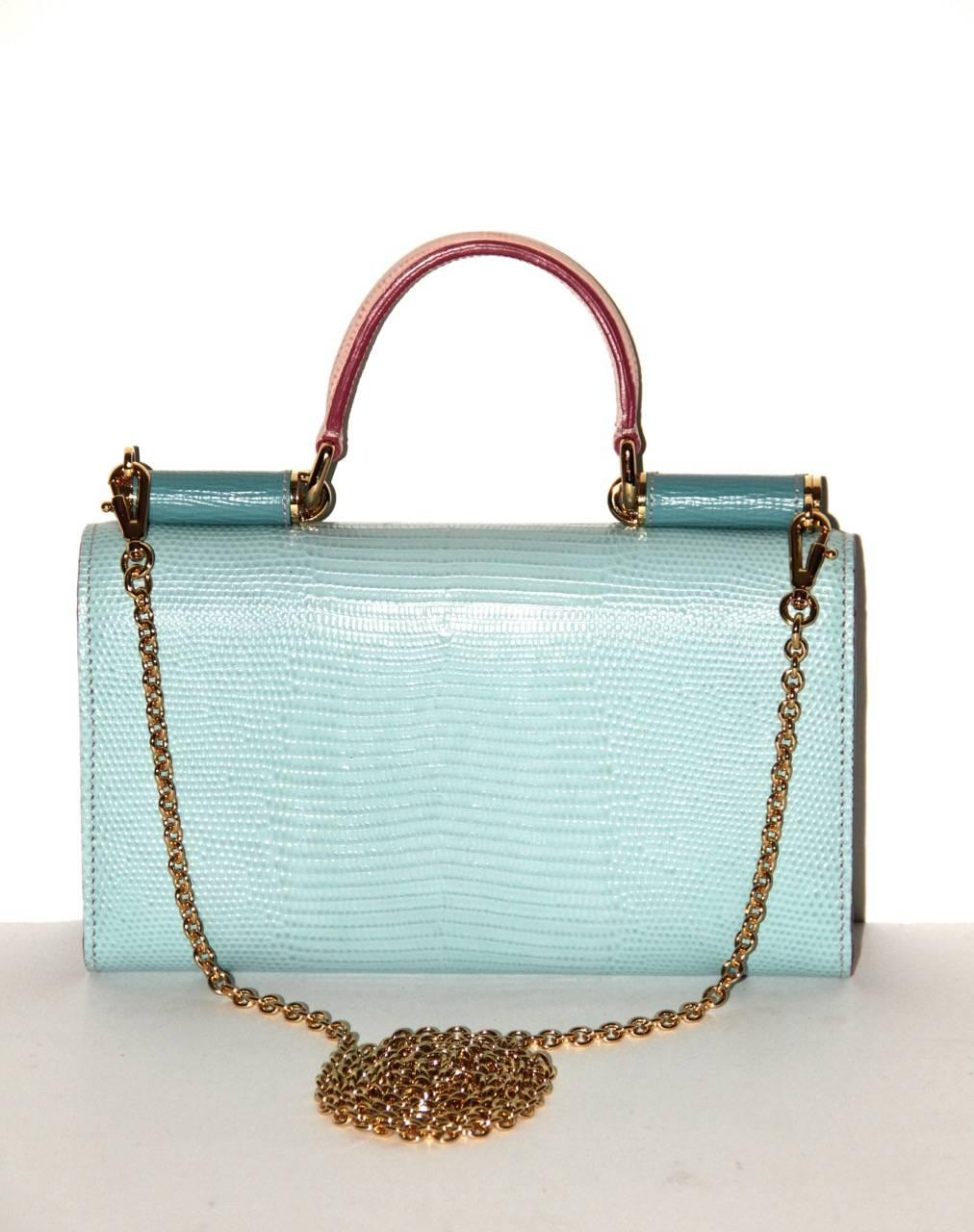 This mini bicolore «Von» crossbody bag is made of iguana-print 2 tone blue and pink texured leather. It features a flap top handle, a removable shoulder chain and a logo plate snap closure at front flap.  
Interior: Blue leather lining, a zip