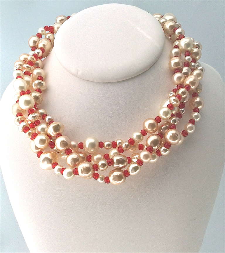 Elegant and rare Chanel necklace with glass elements by Gripoix, made of 4 braided strands of different sized Baroque pearls and small glass ruby red beads, secured by beautifully crafted end caps of gilt metal set with red poured glass, and gold