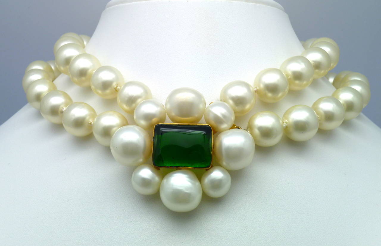 A perfect and dazzling Chanel necklace by Gripoix made of two strands of large  pearls with a large pearl flower in the center. The heart of the flower holds a beautiful large rectangular emerald green poured glass cabochon, with matching cabochons