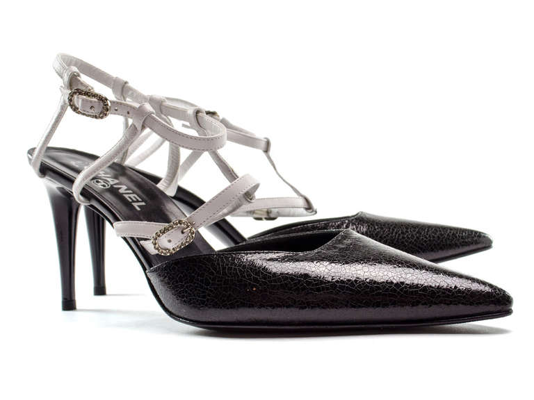 These heels offer a little bit of the past and a bit of the future. Stunning cracked black patent leather covers the vamp of the heels, white leather detailing throughout the straps with rhinestone buckle detail at ankle and foot, infamous CC logo