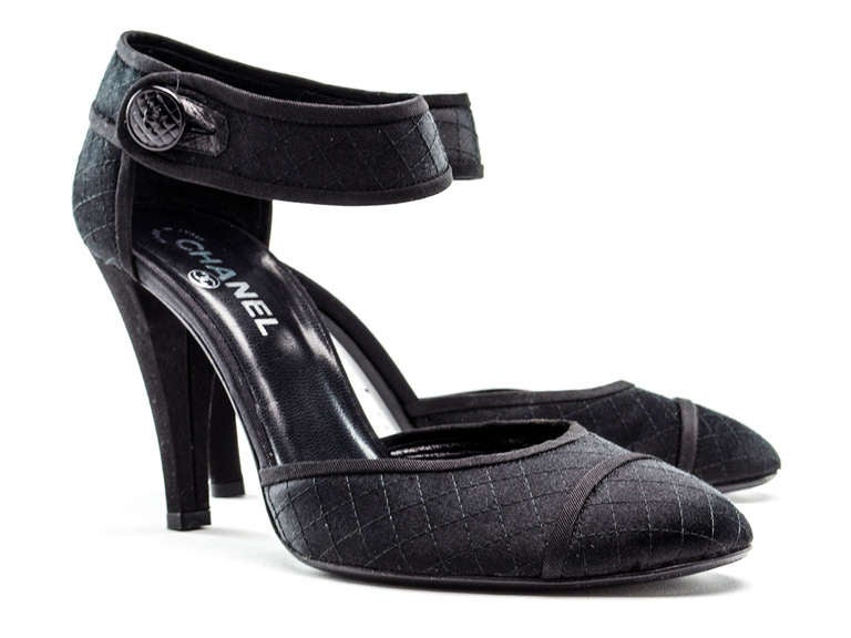 Stunning! Chanel black satin quilted heels feature a round toe, stacked heel, mary jane details, button closure at ankle. Heel measures approximately 4