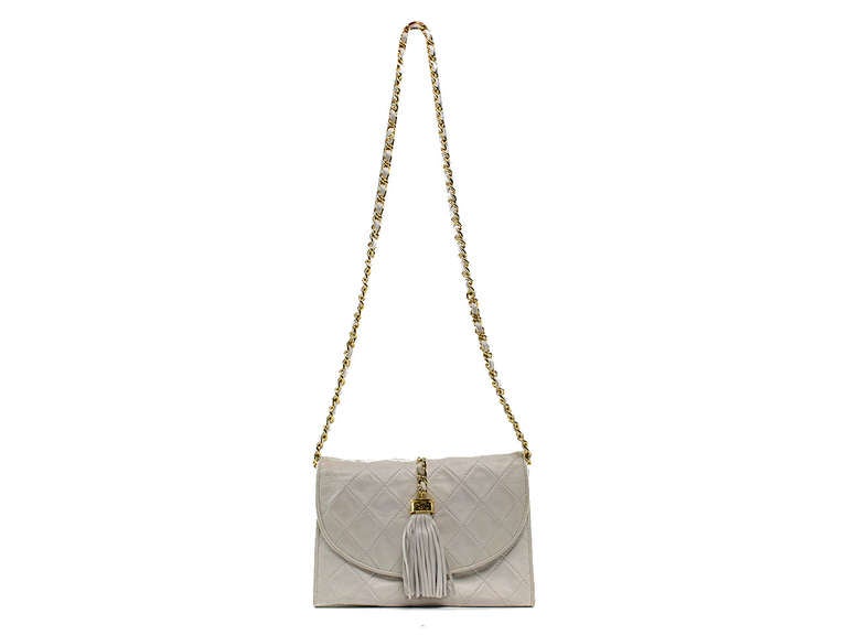 Wear as a clutch or a shoulder bag...this iconic Chanel lambskin flap is sure to stand the test of time! This bag features white lambskin leather throughout, tassel detail at front, gold tone hardware. Interior features one zippered