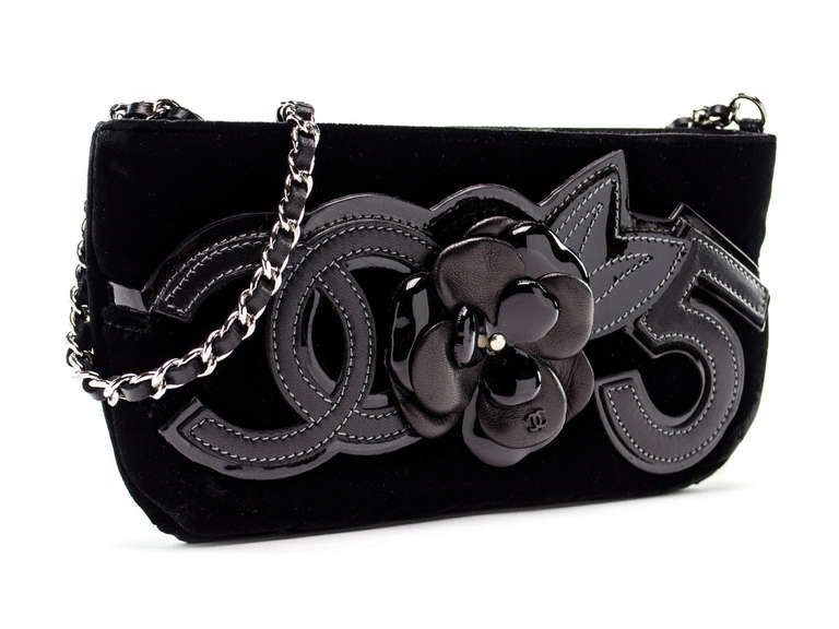 Take this bag for an evening stroll or just for everyday! This Chanel bag features black velvet throughout with the iconic CC insignia at the front, camellia flower and number 5 in black leather. Zip top closure. Interior features one zippered