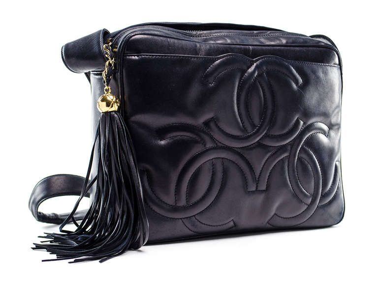 Perfect shoulder bag for everyday! Vintage Chanel black lambskin shoulder bag features three iconic interlocking CC's at the front, front pouch, zip top tassel closure. Interior features one zippered pocket and one pouch pocket. Made in Italy.