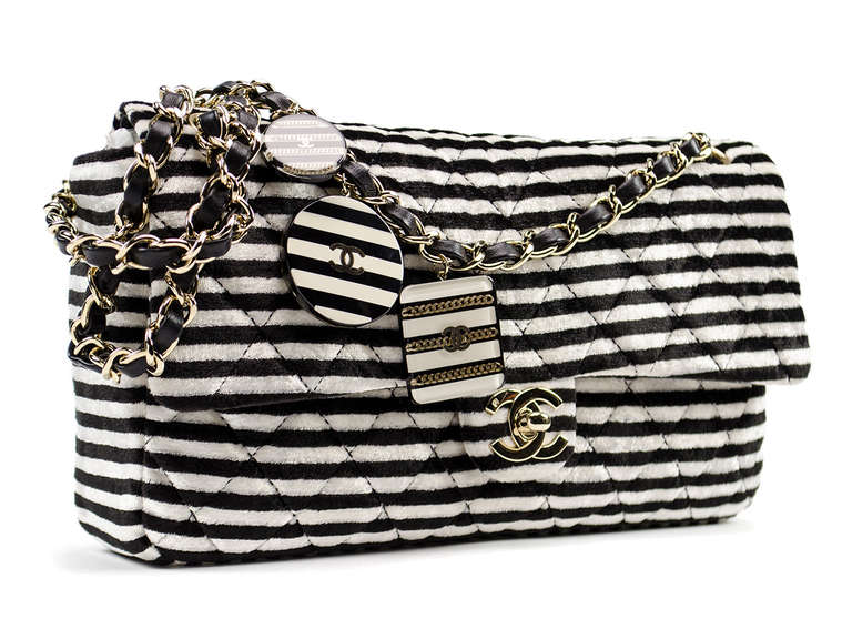 A rare Chanel bag defined by the contrasting white and black velour will be a show stopper wherever you go! Adorned with three charms this bag has the perfect amount of character. Interior features one zip pocket.