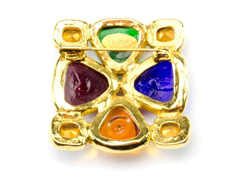 A gorgeous brooch that will be sure to bring out the best in every ensemble! This brooch features poured glass details in hues of red, orange, amber, green and blue with gold tone hardware. Circa season 26.

Includes: Box.

Measurements: 2