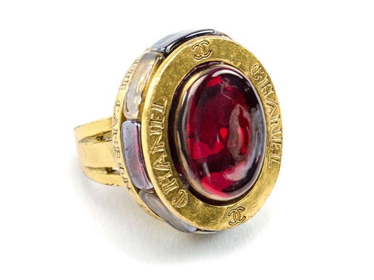 A stunning beauty that is truly one a kind! This ring features red poured glass at it's very center with the 'CC' logo and 'CHANEL' written on the outside, also features poured multi-colored glass around the ring. Fits a size 7-8