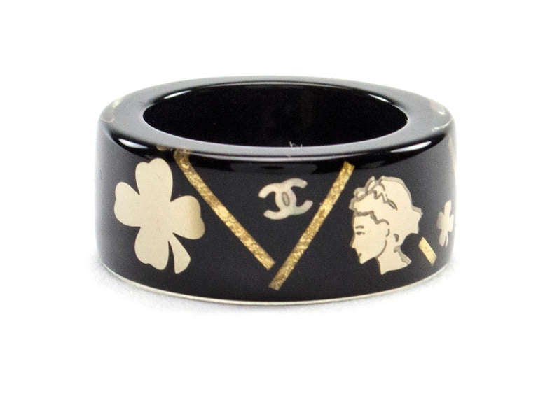 Add a charming statement to any ensemble in this black resin ring! This ring features the interlocking 'CC' logo, four leaf clover and camellia flower in gold on black. Fits a size 5-6 comfortably.

Includes: Box.
