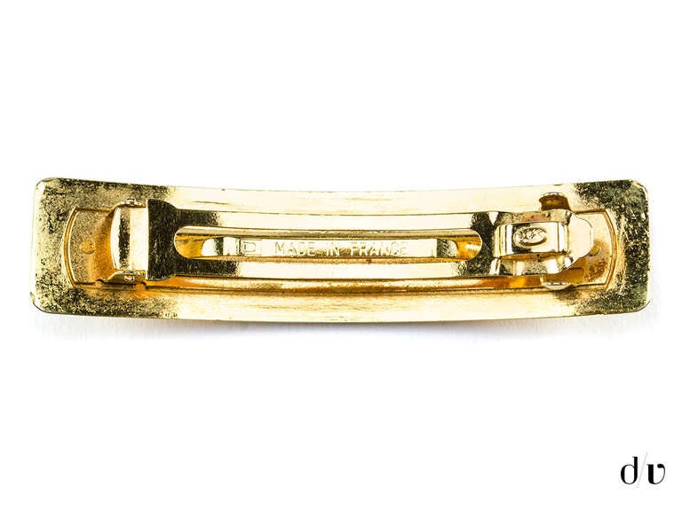 Spice up any outfit with this playful hair barrett! This clip is featured in gold tone with the world 'CHANEL' written across the front. Made in France.

Measurements: 3.75
