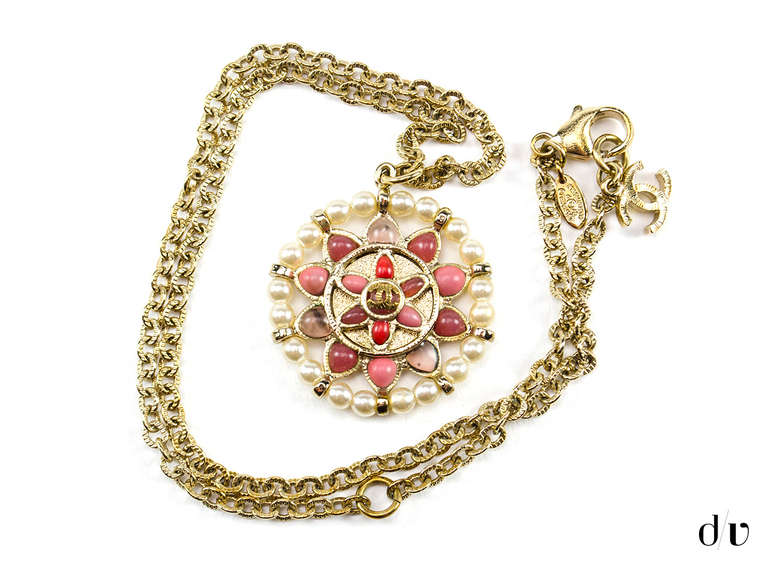 Pair this Chanel tribal necklace with the matching earrings to make a statement! This gold tone necklace features a round pendant with seed pearls and gold round links outer ring; while the inner rings have light and dark pink, salmon and lavender