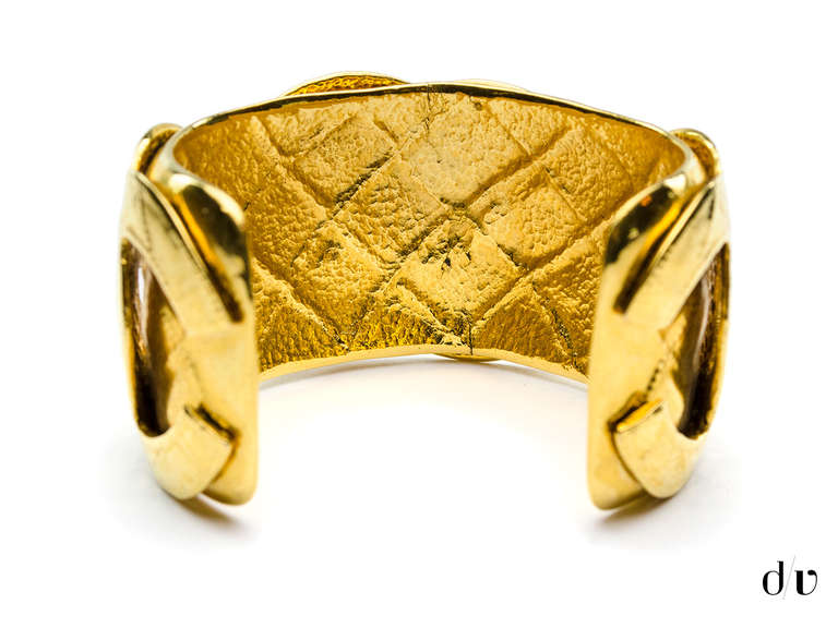 You'll be sure to make a statement in this eye catching Chanel cuff! This cuff features gold quilted detail throughout with three overlaying interlocking 'CC' logo. Note: The Chanel signature is no longer intact. 

Measurements: Diameter measures
