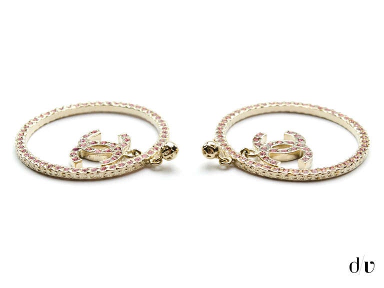 Perfectly sized, these Chanel pink Swarovski earrings will sure to be add a touch of glamour to any ensemble! These earrings feature silver hoop detail throughout, pink Swarovski detail with pink interlocking 'CC' dangling from the center. For