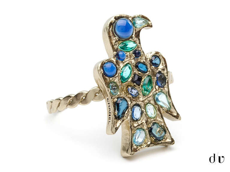 Stunning! Chanel cuff features a gorgeous tribal bird detail with blue and green jeweled details with a small interlocking 'CC' logo on the side on a silver cuff. Open cuff at the back.

Measurements: Measures 2