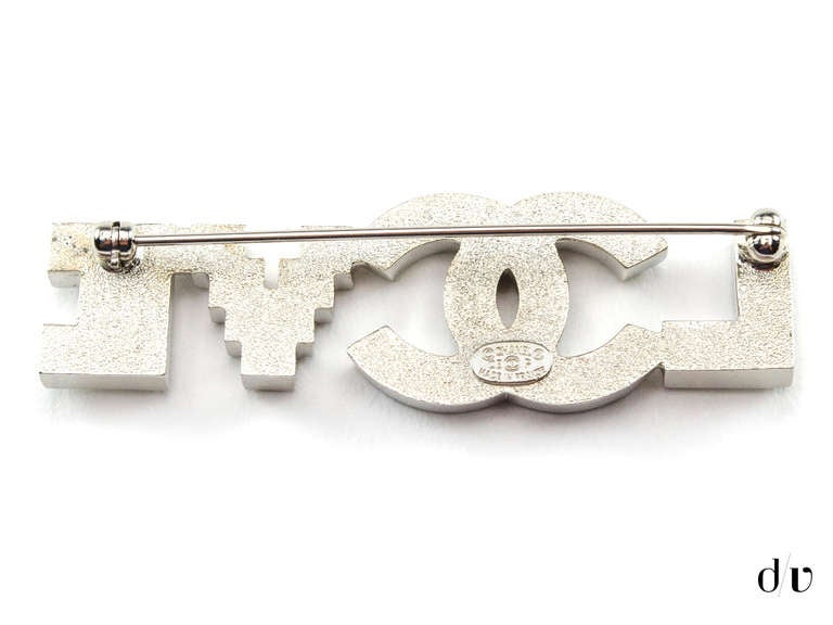 Extremely rare! Chanel 'LOVE' brooch will be sure to add a touch of glamour to any ensemble! This brooch features Swarovski crystal with interlocking 'CC' detail substituting as the 'O'.