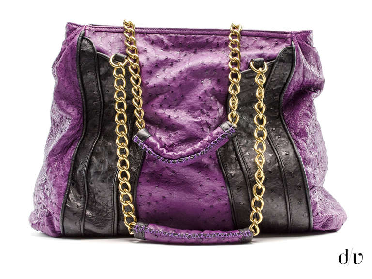 Make a statement in this eye catching Zac Posen bag! Featured in purple/black ostrich it will be sure to be a show stopper! This bag also features gold tone hardware throughout, front drawstring pocket. Interior features one zippered pocket and two