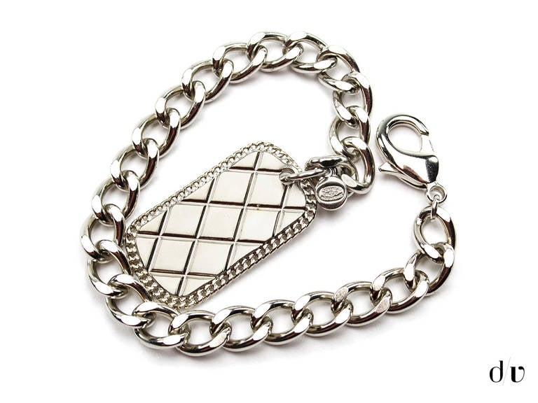 Add a distinctive look to your style with this unique Chanel dog tag necklace. Necklace features silver tone hardware, quilted detail on tag with black interlocking 'CC' logo on the front. Clasp closure. Made in France.

Includes: