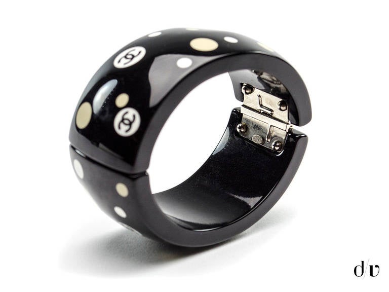 Add a hint of playfulness to any outfit with this fun loving Chanel polka dot cuff! Cuff is featured in black resin with ivory and beige polka dots throughout with interlocking CC detail in black. Made in France.

Includes: Box.

Measurements: