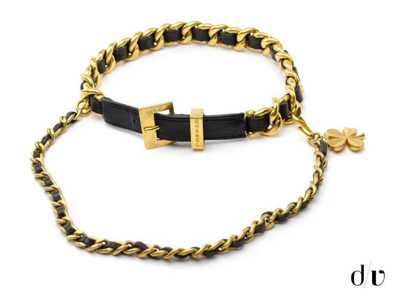 Designed in the 1990s and inspired by Victoire de Castellane, the black leather and brushed gold plated metal necklace features a woven chain design with buckle closure. Additional strand has a a clover charm at the end that hooks to the main strand