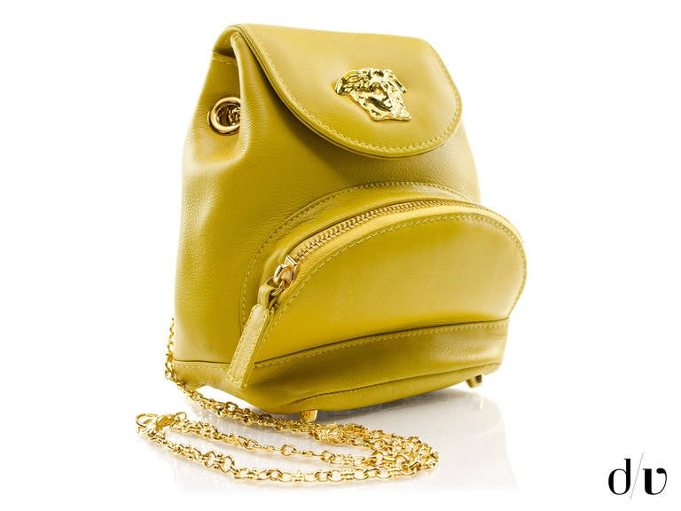 Make a statement in this rocker chic vintage Gianni Versace backpack in yellow. This bag features yellow leather throughout, gold tone hardware, one interior front pocket, four feet at bottom of the bag, button closure at the front and Gianni