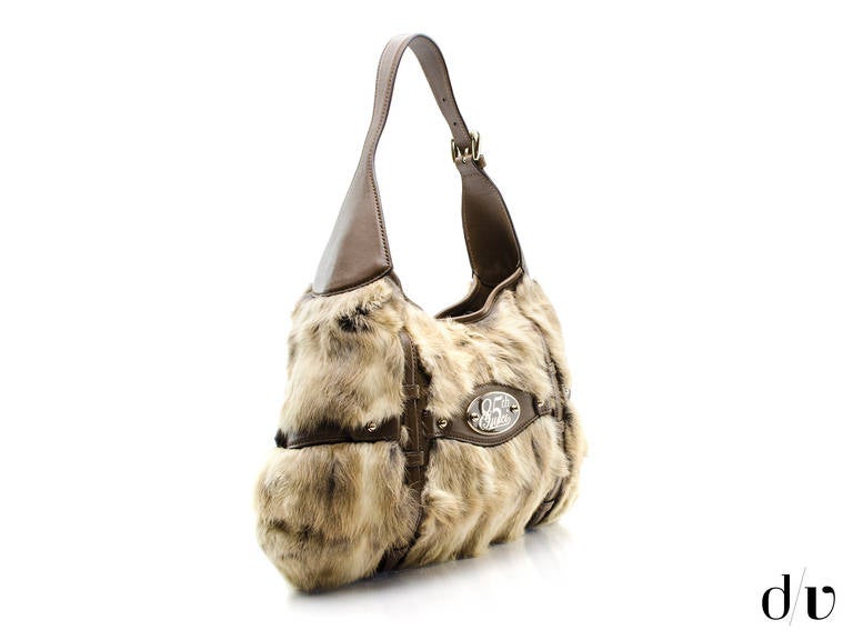 This Gucci Limited Edition 85th Anniversary Shoulder Bag is done in fur. The brown leather handle boasts an 8 inch handle drop. The hardware is done in gold. The magnetic snap closure secures the monogram canvas interior that boasts one zipper