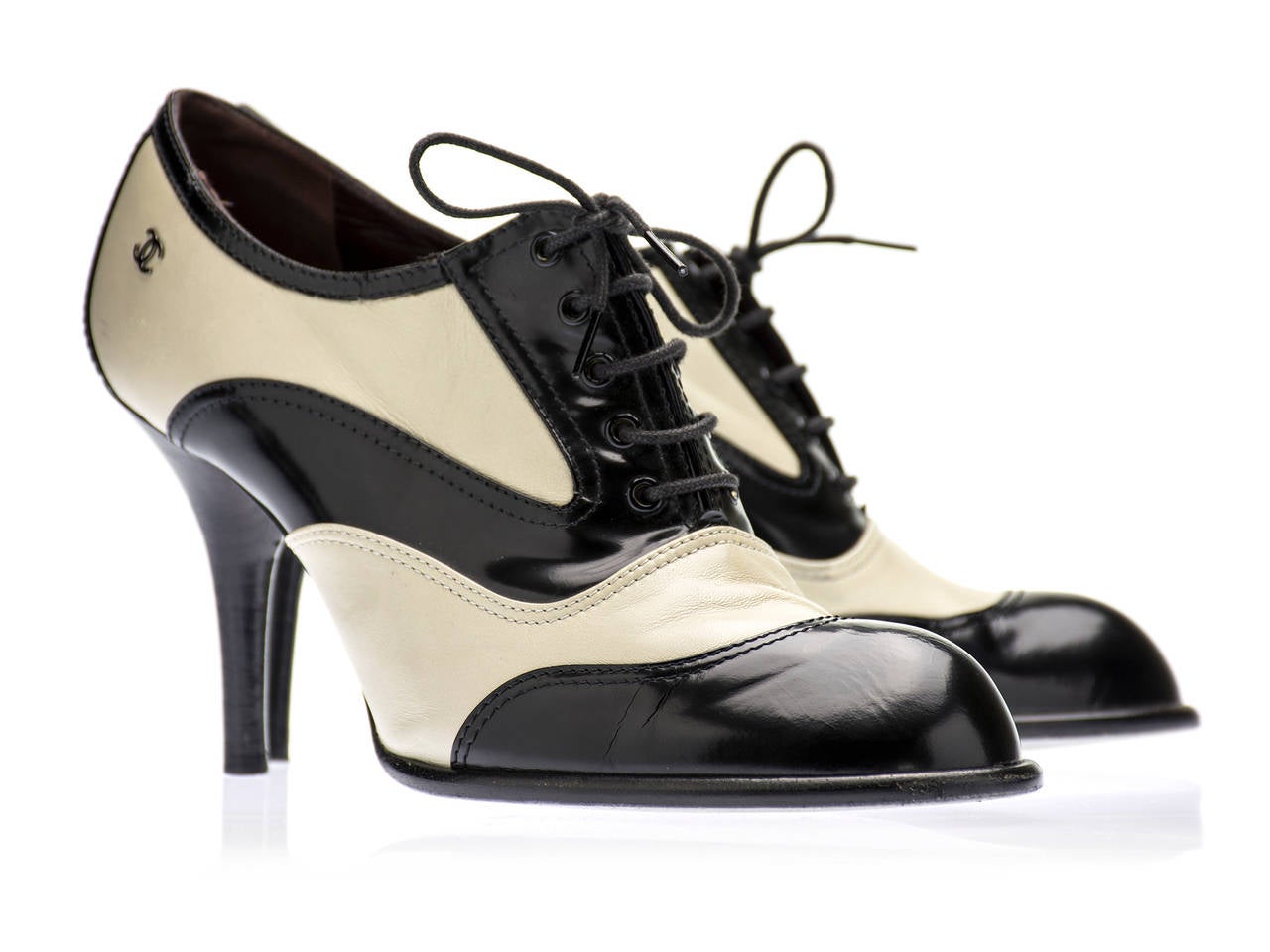 This two tone black and cream patent leather heel is classy and definitely head turning! Classic round toe with a lace up design and contrasting color combination reminisces vintage shoe style of the 30s. A silver CC logo on the side of the shoe.