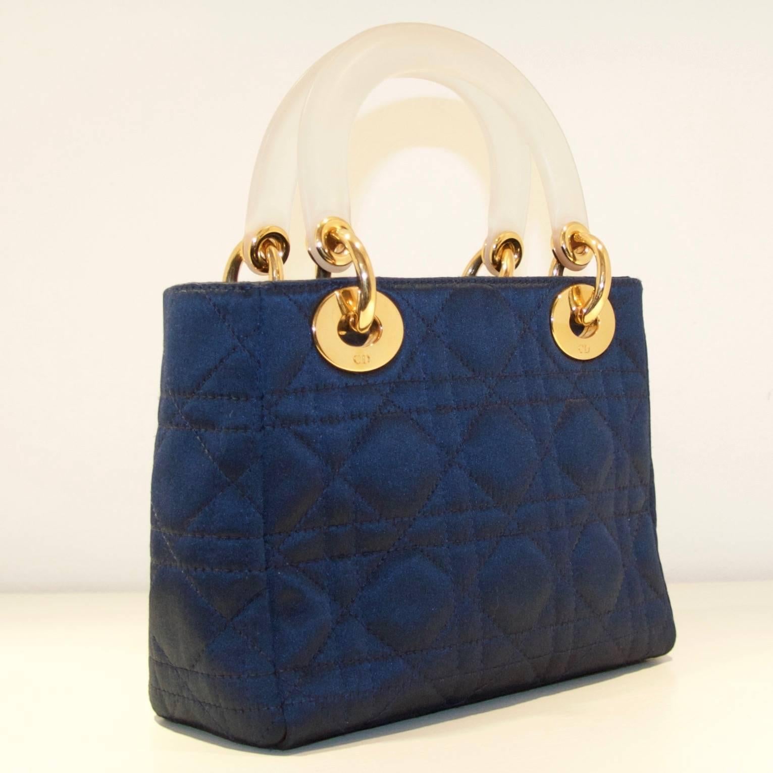 Christian Dior Micro Lady Dior 1997 

Small quilted navy tote with diamante  (Swarovski) crystal insert on the logo.
Gold hardware with lucite handles and top flap closure. 
Dior monogrammed gold satin lining with zip pocket.

Serial number: