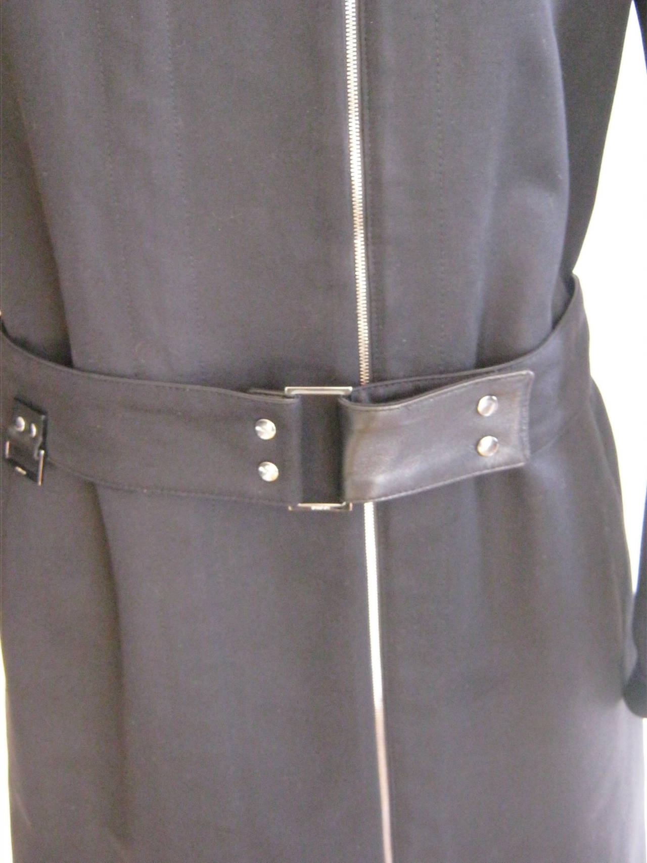 100% heavy cotton this trench coat has a number of unusual details such as a side zipper fastening; leather cuff trim and inside seams; adjustable snap belt with one side cotton and the other leather; two slant pockets;  snap silver detailing with