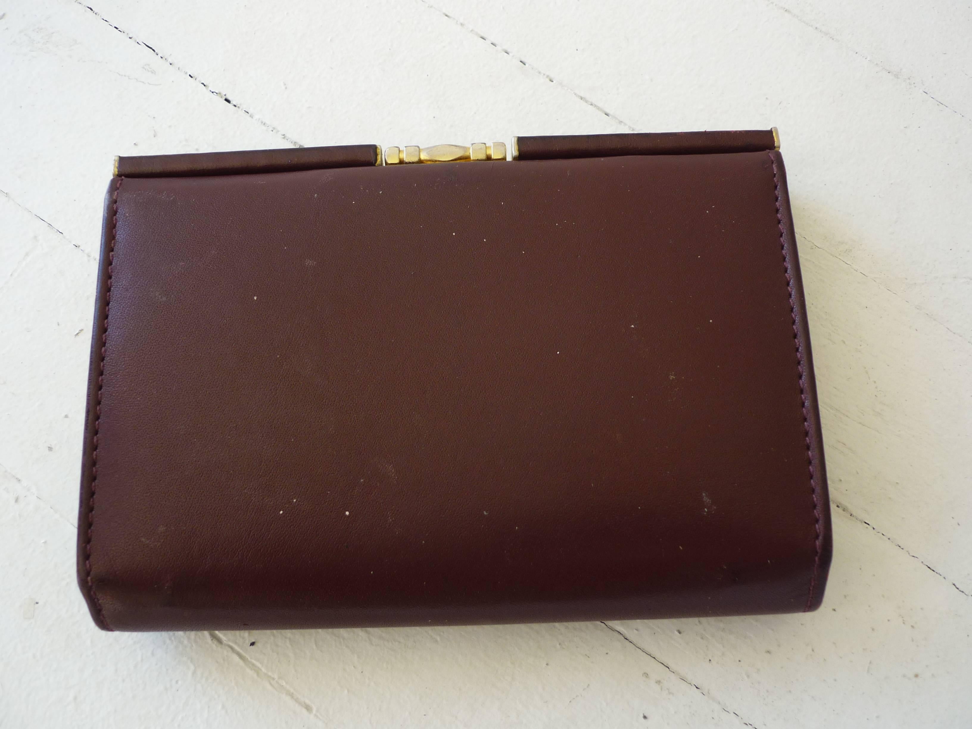 A wallet and a separate coin compartment in bordeaux leather with gold tone accent and kiss-lock closure.

Apart from the full size change compartment, the wallet features two separate billfolds and a clear plastic slot on the side. 

There is