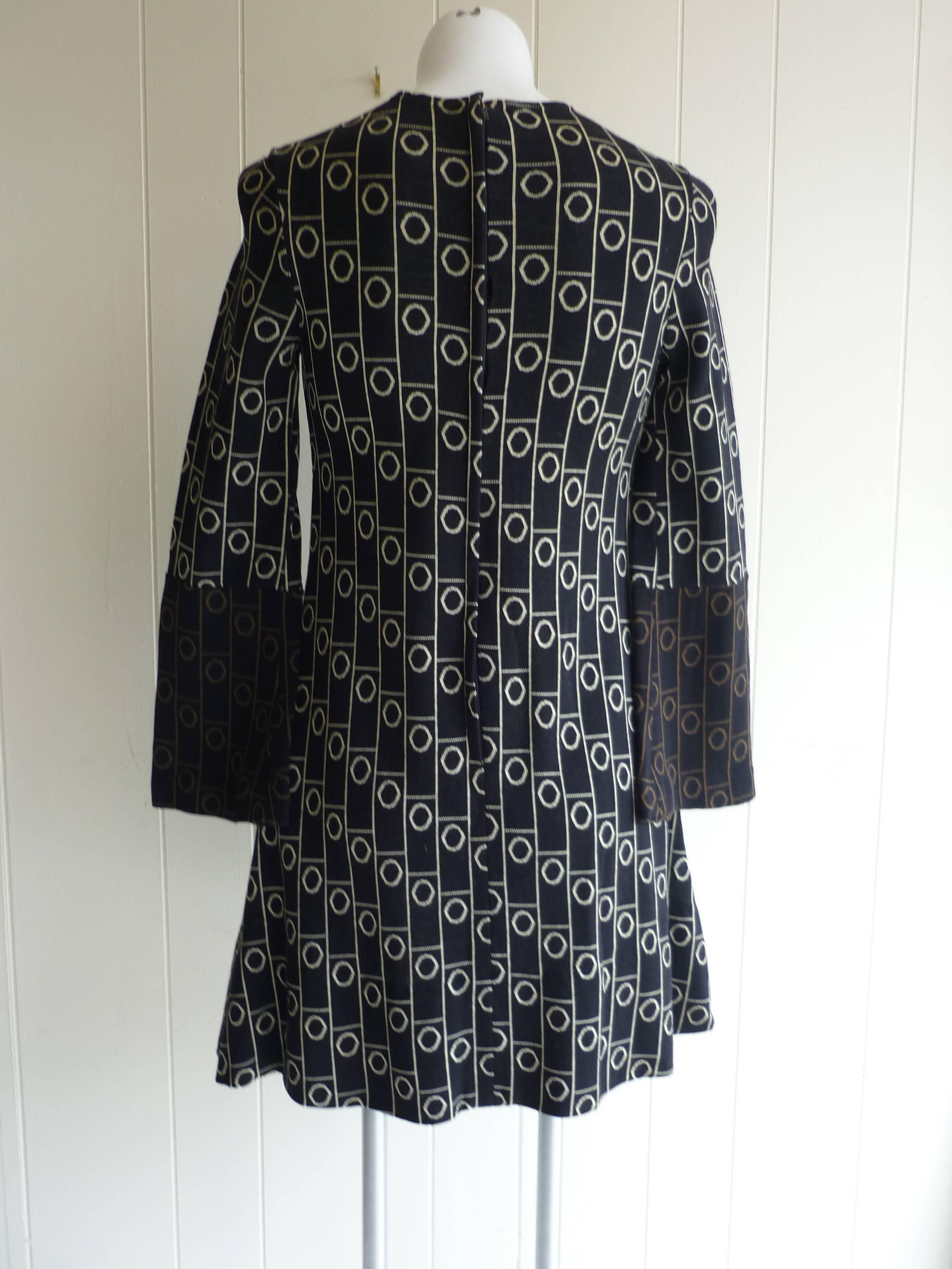 A collector dress in excellent condition, this wool dress has a black background with two-tone bell sleeves (black and beige and black and brown); a round collar, and makes you want to play tic tac toe.

The material is stretchy.

A beautiful