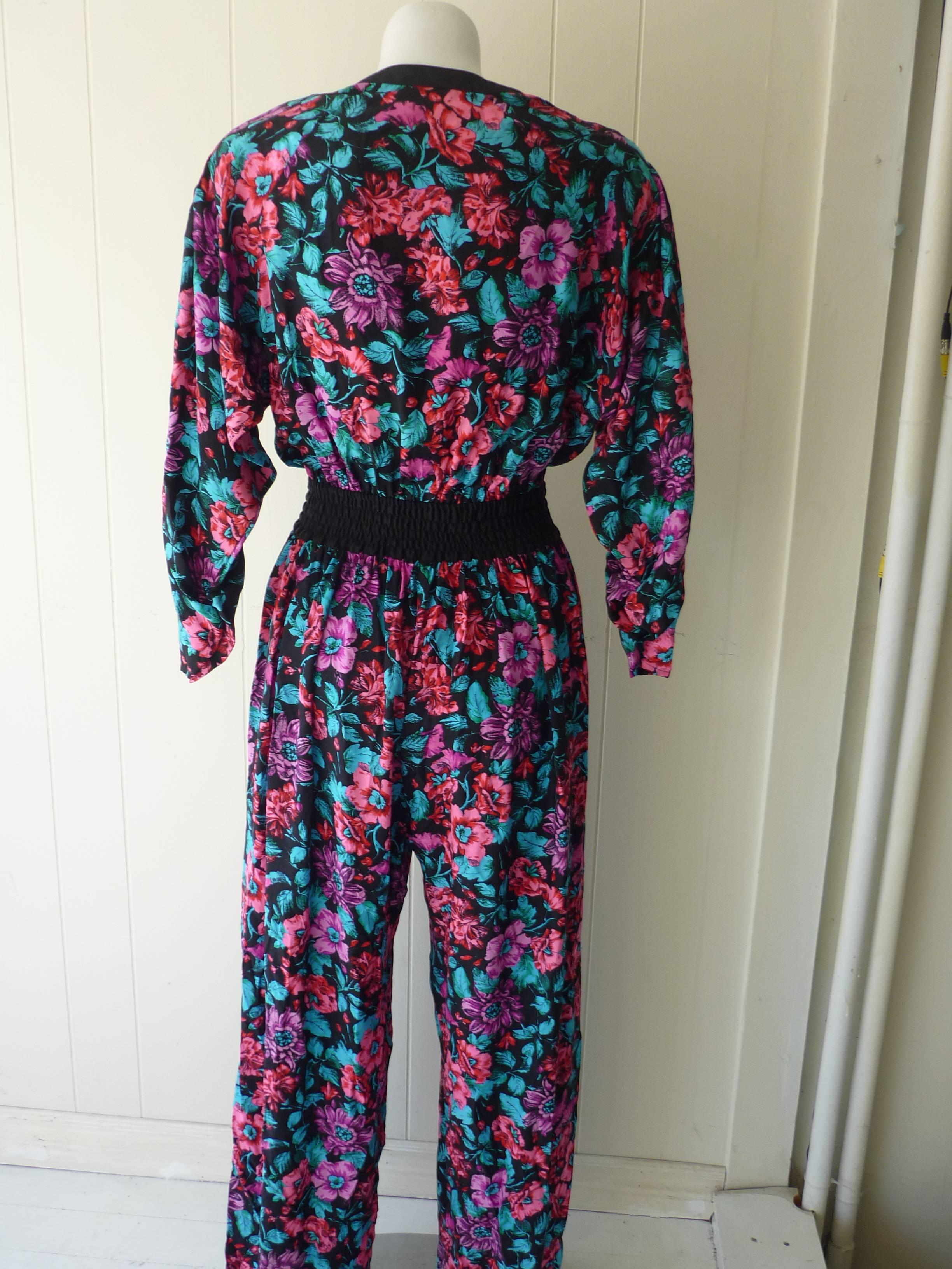 This silk floral print jumpsuit with palazzo legs and padded shoulders is typical of Diane Freis's Boho style.

The sleeves are gathered and come to a point; closures is by a gold and diamante button and hidden buttons; the waist is elasticized